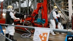 FILE - Workers drill pipes into the ground to be used to create a frozen underground wall to surround the crippled reactor buildings at Tokyo Electric Power Co.'s Fukushima Daiichi Nuclear Power Plant in Okuma, Fukushima Prefecture, northeast of Tokyo, Ja