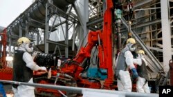 FILE - Workers drill pipes into the ground to be used to create a frozen underground wall to surround the crippled reactor buildings at Tokyo Electric Power Co.'s Fukushima Daiichi Nuclear Power Plant in Okuma, Fukushima Prefecture, northeast of Tokyo, Japan.