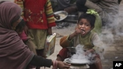 An Indian homeless child eats food as his mother cooks by a road side on a cold and foggy morning in Allahabad, India, Tuesday, Dec. 20, 2011. 