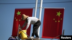 Workers hang up Chinese flags on a street ahead of the 70th founding anniversary of People's Republic of China in Kunming, Yunnan province, China, Sept. 22, 2019. 