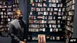 FILE—French President Emmanuel Macron looks at the images of genocide victims on display during his visit to the Kigali Genocide Memorial, where some 250,000 victims of the massacres are buried, in Kigali on May 27, 2021.