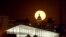 In this Wednesday, April 8, 2020 photo, the super moon rises behind the state Capitol in Denver.