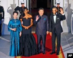 President Barack Obama and Chinese President Xi Jinping wave on the North Portico with wives Peng Liyuan and Michelle Obama as they arrive for a State Dinner at the White House in Washington, Sept. 25, 2015.