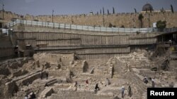 Members of the media and workers from Israel's antiquity authority stand at a site that archaeologists say contains the remnants of an ancient Greek fortress, outside the walled Old City of Jerusalem, Nov. 3, 2015. 