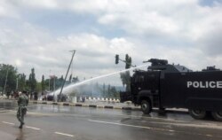 Police use water cannons to disperse people protesting against alleged brutality by members of Nigeria's Special Anti-Robbery Squad (SARS), in Abuja, Nigeria, Oct. 11, 2020.