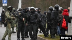 Para petugas keamanan Belarus menyaksikan para demonstran berdemo menolak hasil pilpres di Minsk, Belarus, Minggu, 22 November 2020. (Foto: Reuters)