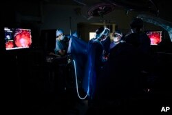 Dr. Sunil Singhal, center right, views a monitor to look at a tumor in his patient, made visible with the use of a special camera and fluorescent dye