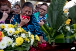 In this Oct. 31, 2018 photo, Haydee Posadas cries during the burial service for her son Wilmer Gerardo Nunez, at a cemetery in San Pedro Sula, Honduras.