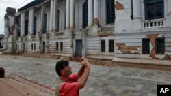 Tourist photographs a damaged building near Basantapur Durbar Square in Kathmandu, Nepal, June 15, 2015.