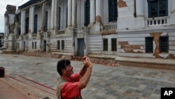 Turis memotret gedung rusak dekat Alun-alun Basantapur Durbar di Kathmandu, Nepal (15/6). (AP/Niranjan Shrestha)