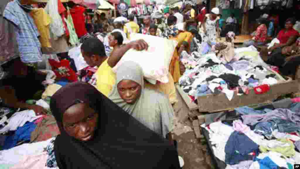 Women walk past people buying second hand clothes at Katangua market in Lagos.