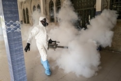 In this Wednesday, April 1, 2020, photo, a municipal worker sprays disinfectant in a mosque to help curb the spread of the new coronavirus in Dakar, Senegal.