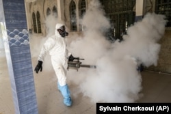 In this Wednesday, April 1, 2020, photo, a municipal worker sprays disinfectant in a mosque to help curb the spread of the new coronavirus in Dakar, Senegal.