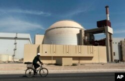 Seorang pekerja mengendarai sepeda di depan gedung reaktor pembangkit listrik tenaga nuklir Bushehr, tepat di luar kota selatan Bushehr, Iran, 26 Oktober 2010. (Foto: AP)