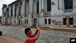 Du khách chụp ảnh một tòa nhà bị hư hại gần Basantapur Durbar Square ở Kathmandu, Nepal, ngày 15/6/2015.