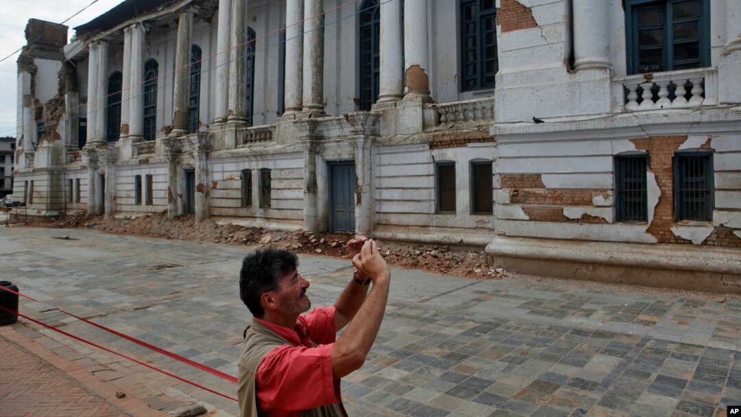 Turis memotret gedung rusak dekat Alun-alun Basantapur Durbar di Kathmandu, Nepal (15/6). (AP/Niranjan Shrestha)