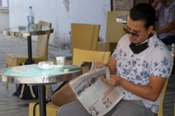A Tunisian man reads the newspaper on the Habib Bourguiba avenue in Tunis on July 27, 2021.
