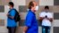People wear face masks to protect against the coronavirus as they keep their distance in a queue at a supermarket during a mandatory confinement, in San Juan, Puerto Rico on April 7, 2020.