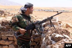 FILE - Iraqi Kurdish Peshmerga fighters take position as they monitor the area from their front line position in Bashiqa, a town 13 kilometers northeast of Mosul, Aug.12, 2014.