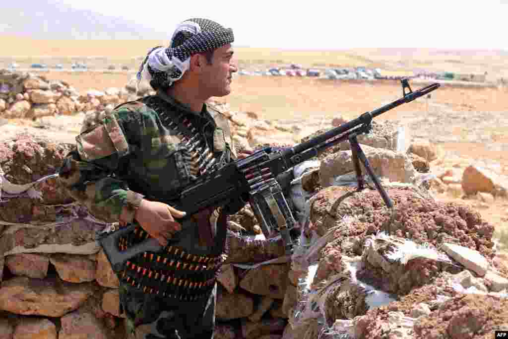 Iraqi Kurdish Peshmerga fighters take position as they monitor the area from their front line position in Bashiqa, a town 13 kilometers north-east of Mosul, Aug.12, 2014.