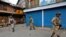 Indian policemen stand guard in front of the closed shops during a curfew in Srinagar, July 13, 2016. 