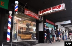 Men queue for a haircut outside a barber shop in Melbourne, Oct. 19, 2020. (AFP)