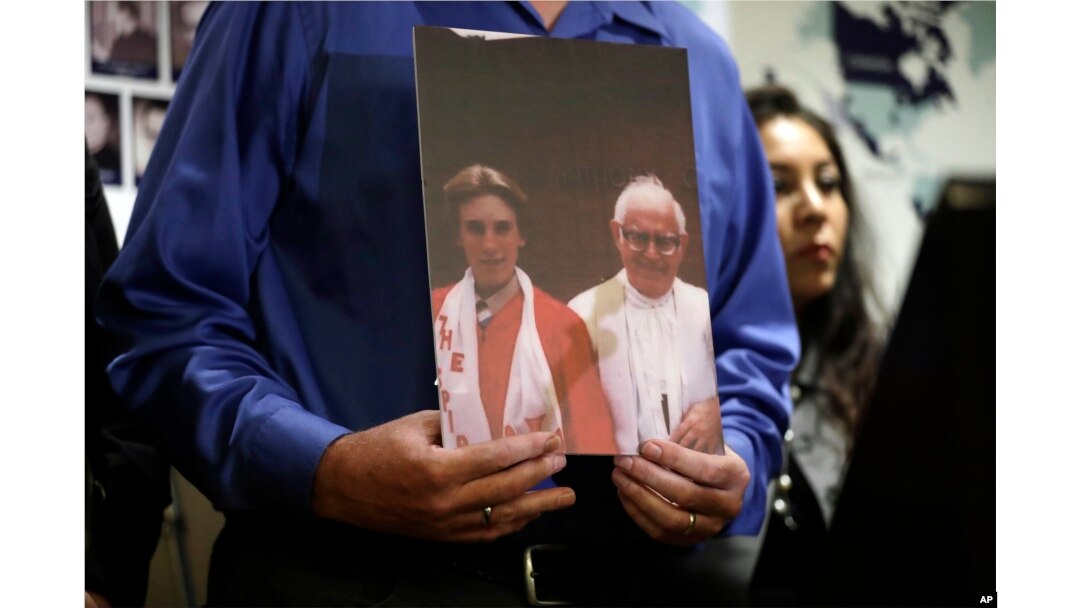 Tom Emens holds a picture of himself as a boy with, Monsignor Thomas Joseph Mohan, the priest who sexually abused him in the late 70s during a press conference, Oct. 2, 2018, in Los Angeles.