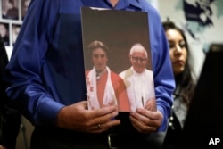 Tom Emens holds a picture of himself as a boy with, Monsignor Thomas Joseph Mohan, the priest who sexually abused him in the late 70s during a press conference, Oct. 2, 2018, in Los Angeles.