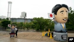 Tư liệu: Một nhà hoạt động dựng bảng chỉ trích Thủ tướng Shinzo Abe trước một nhà máy nhiệt điện than tại hội nghị thượng đỉnh G20 27/9/2019. Giới hoạt động đòi Tokyo ngưng tài trợ cho các nhà máy nhiệt điện than ở nước ngoài. (AP Photo/Jae C. Hong)
