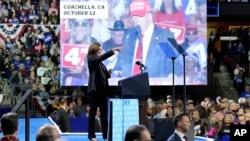 FILE - Democratic presidential nominee Vice President Kamala Harris speaks as an image of Republican presidential nominee former President Donald Trump is seen on screen during a campaign rally in Erie, Pennsylvania, Oct. 14, 2024.