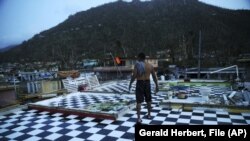 In this Sept. 26, 2017 file photo, Nestor Serrano walks on the upstairs floor of his home, where the walls were blown off, in the aftermath of Hurricane Maria, in Yabucoa, Puerto Rico.