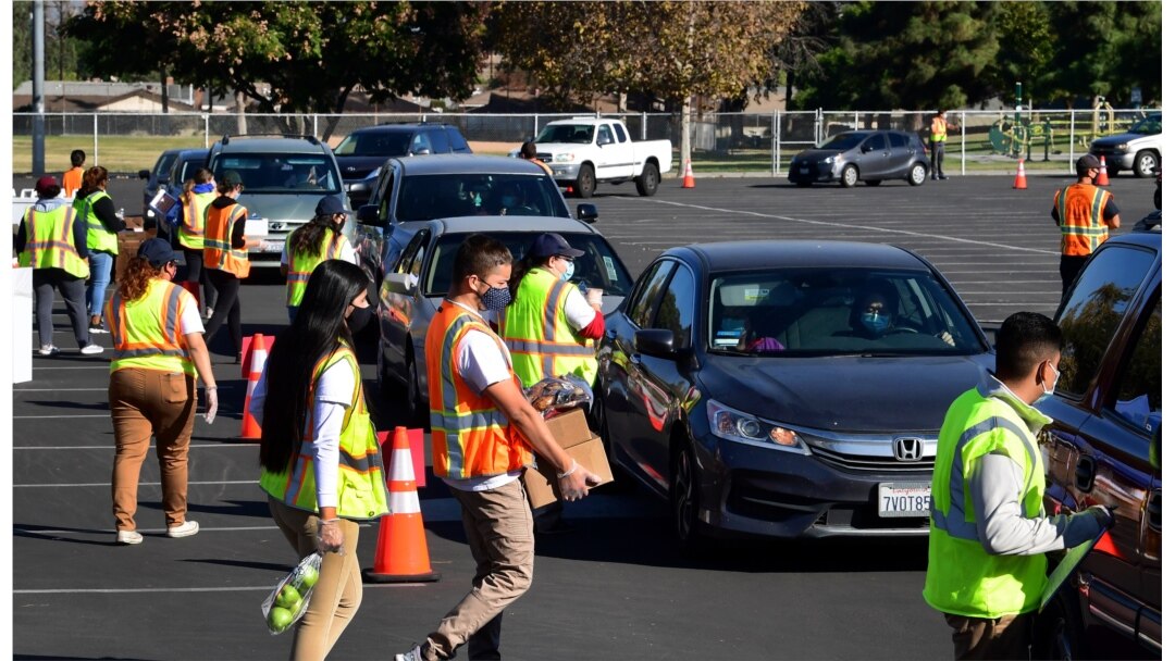 FILE - In this file photo taken on Dec. 04, 2020, food is loaded as drivers in their vehicles wait in line on arrival at a "Let's Feed LA County" food distribution hosted by the Los Angeles Food Bank in Hacienda Heights, California.