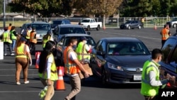 FILE -Food is loaded as drivers in their vehicles wait in line on arrival at a "Let's Feed LA County" food distribution hosted by the Los Angeles Food Bank in Hacienda Heights, California, Dec. 4, 2020.