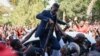 Ugandan pop star turned opposition MP, Robert Kyagulanyi, is helped by his supporters as he delivers a speech outside his home in Kampala, Uganda, after returning from the United States on Sept. 20, 2018.