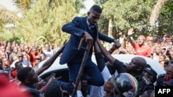 Ugandan pop star turned opposition MP, Robert Kyagulanyi, is helped by his supporters as he delivers a speech outside his home in Kampala, Uganda, after returning from the United States on Sept. 20, 2018.