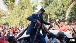 Ugandan pop star turned opposition MP, Robert Kyagulanyi, is helped by his supporters as he delivers a speech outside his home in Kampala, Uganda, after returning from the United States on Sept. 20, 2018.