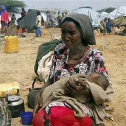 A woman sits with her baby in an open area near a camp in Mogadishu, Somalia, earlier this summer.