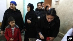 An Egyptian woman registers to vote while others are lining up at a polling center in Giza, Egypt, December 21, 2011.