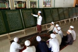 FILE - A teacher explains verses of the Quran imprinted on metal plates at a recital class during the holy fasting month of Ramadan at the Al-Ashriyyah Nurul Iman Islamic boarding school in Parung, West Java, Indonesia,