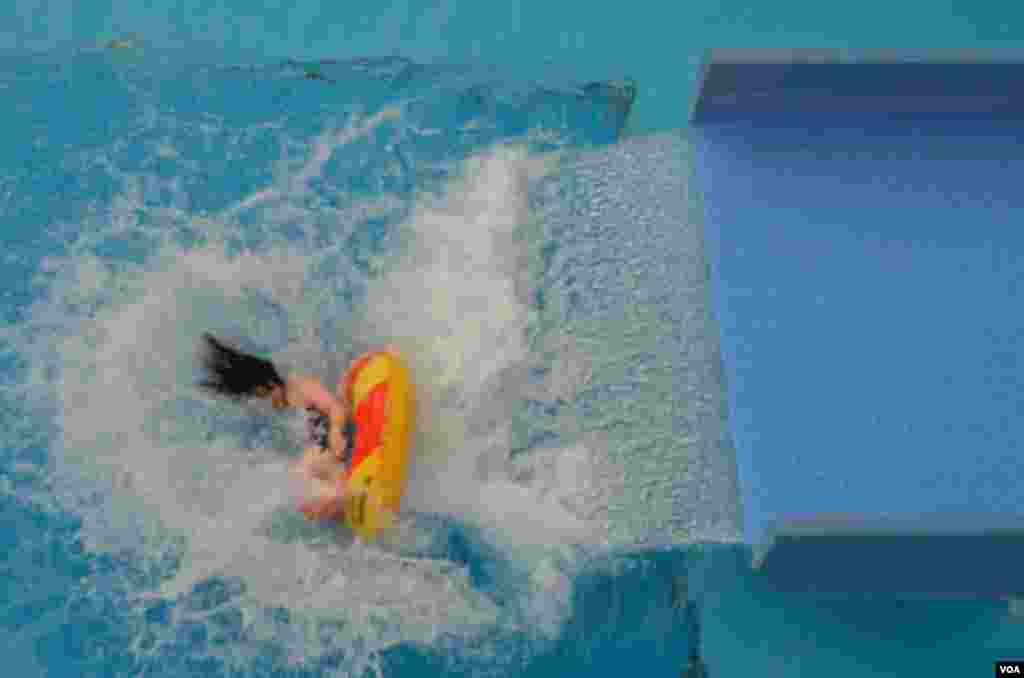 A young woman comes to the end of her ride on a water slide, October 25, 2012. (Steve Herman/VOA)