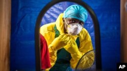 FILE -A healthcare worker dons protective gear before entering an Ebola treatment center in the west of Freetown, Sierra Leone, Oct. 16, 2014.