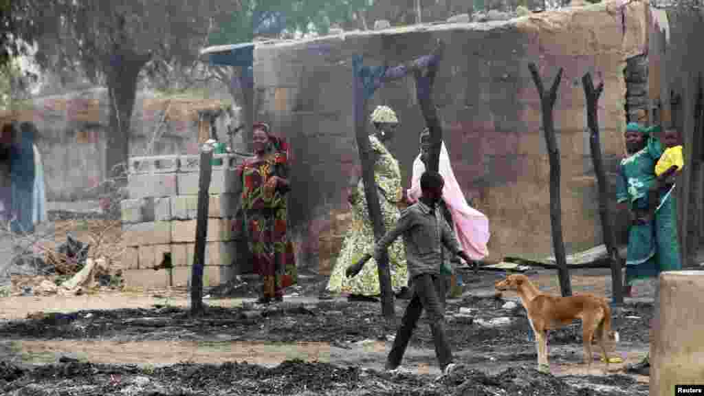 People stand near burnt structures in the aftermath of what Nigerian authorities said was heavy fighting between security forces and Islamist militants in Baga.