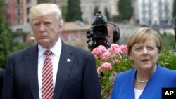 FILE - US President Donald Trump is flanked by German Chancellor Angela Merkel during the G7 meeting in Taormina, Italy, May 26, 2017. 