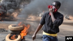 A man holds a hat over his mouth as black smoke billows from tires set on fire in Niamey after police fired teargas to disperse a banned opposition demonstration in the Niger capital, Jan. 18, 2015.