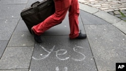 A person walks by a message left by a member of the 'Yes' campaign written on a pavement, in Edinburgh, Scotland, Sept. 17, 2014. 