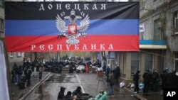 Aktivis pro-Rusia berkumpul di kantor polisi yang mereka duduki dengan banner bertuliskan "Republik Donetsk" di Slovyansk, hari Minggu, 13 April 2014.