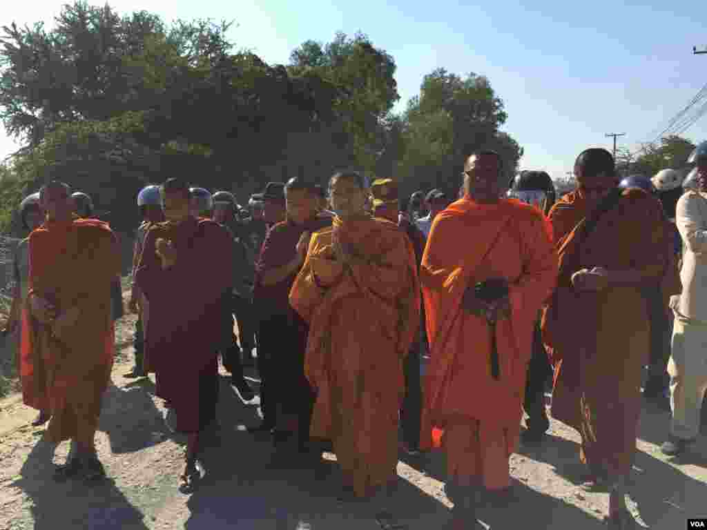 Venerable Luon Sovath, second from right, a monk and human rights defender, with camera in hand walks on after he was pushed off the street by security personnel, on Sunday January 3rd, 2016. (Hul Reaksmey/VOA Khmer)