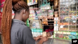 FILE —Joseph Kuraru, a 26 year-old kiosk owner in Nairobi, Kenya, serves a customer a kilo of sugar on Friday, October 27, 2023. The amount of sugar milled in Kenya fell steadily from June to August. To compensate, monthly imports doubled from September to October.