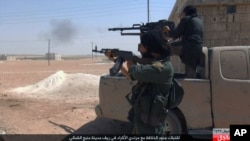 FILE - This undated image posted online July 18, 2016, by supporters of the Islamic State militant group on an anonymous photo-sharing website shows Islamic State fighters firing their weapons during clashes with the Kurdish-led Syrian Democratic Forces in Manbij, in Aleppo province, Syria. Rebels and pro-government forces were battling for control of the northern metropolis.