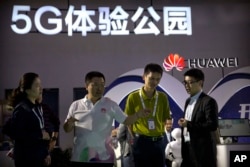 ພວກຜູ້ທ່ຽວຊົມ ກຳລັງເບິ່ງ ໂທລະສັບມືຖື ລະບົບເທັກໂນໂລຈີ 5G ຈາກ Huawei ບໍລິສັດເທັກໂນໂລຈີຂອງຈີນ ຢູ່ທີ່ງານວາງສະແດງສິນຄ້າເທັກໂນໂລຈີ PT Expo ໃນນະຄອນຫຼວງ ປັກກິ່ງ ຂອງຈີນ, ວັນທີ 26 ກັນຍາ 2018.